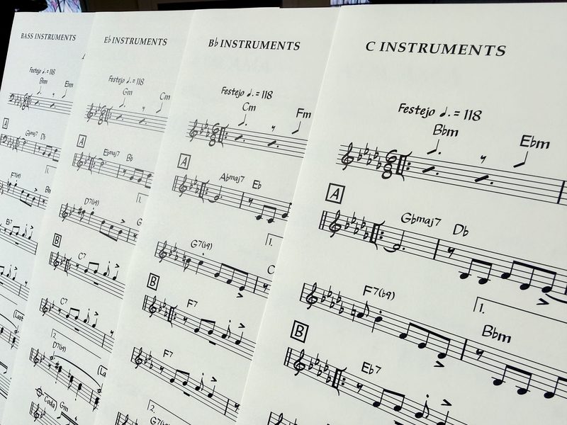 Four lead sheets of the same tune fanned out, headed C Instruments, B flat Instruments, E flat Instruments and Bass Instruments.