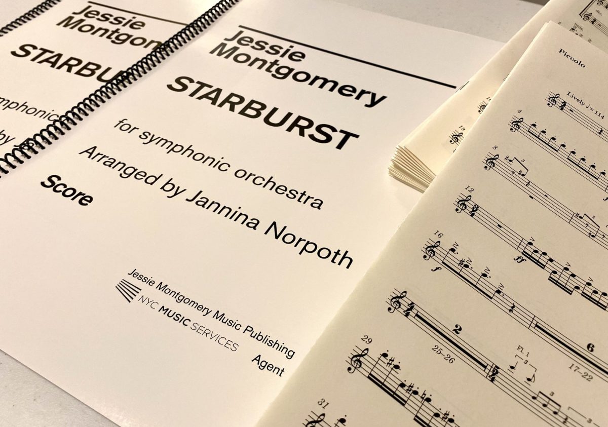 Two spiral-bound scores headed Jessie Montgomery, Starburst, for symphonic orchestra, arranged by Jannina Norpoth, carrying the imprint Jessie Montgomery Music Publishing with NYC Music Services as agent, beside a fanned stack of printed parts opened at the piccolo part.