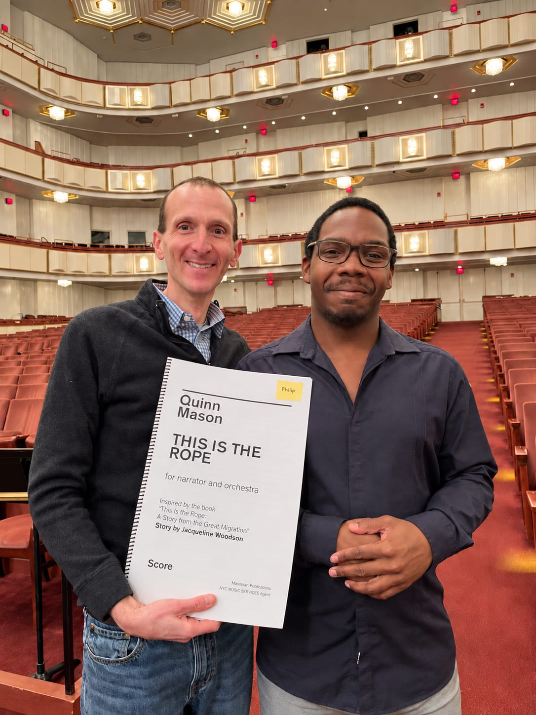 Philip Rothman and Quinn Mason in a concert hall, holding the score of This Is the Rope.